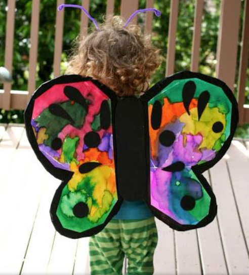 Child wearing colorful butterfly wings outdoors.