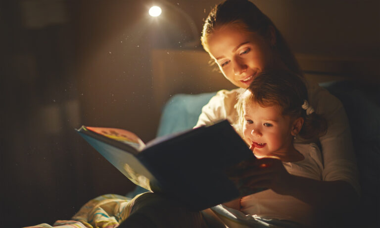 A mother reads a bedtime story to her child under soft lighting.
