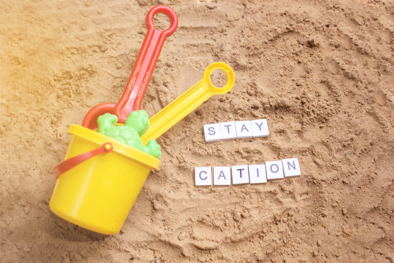 Colorful beach toys with 'Stay Caution' spelled out on sand.