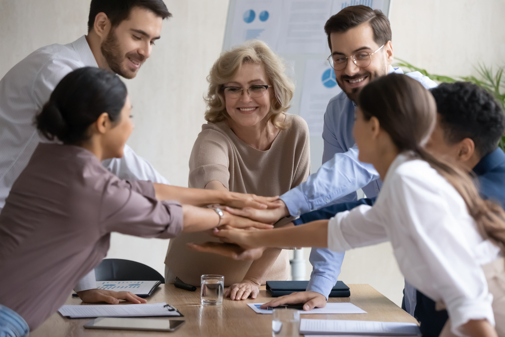 Team of diverse coworkers joining hands in a show of unity and collaboration.